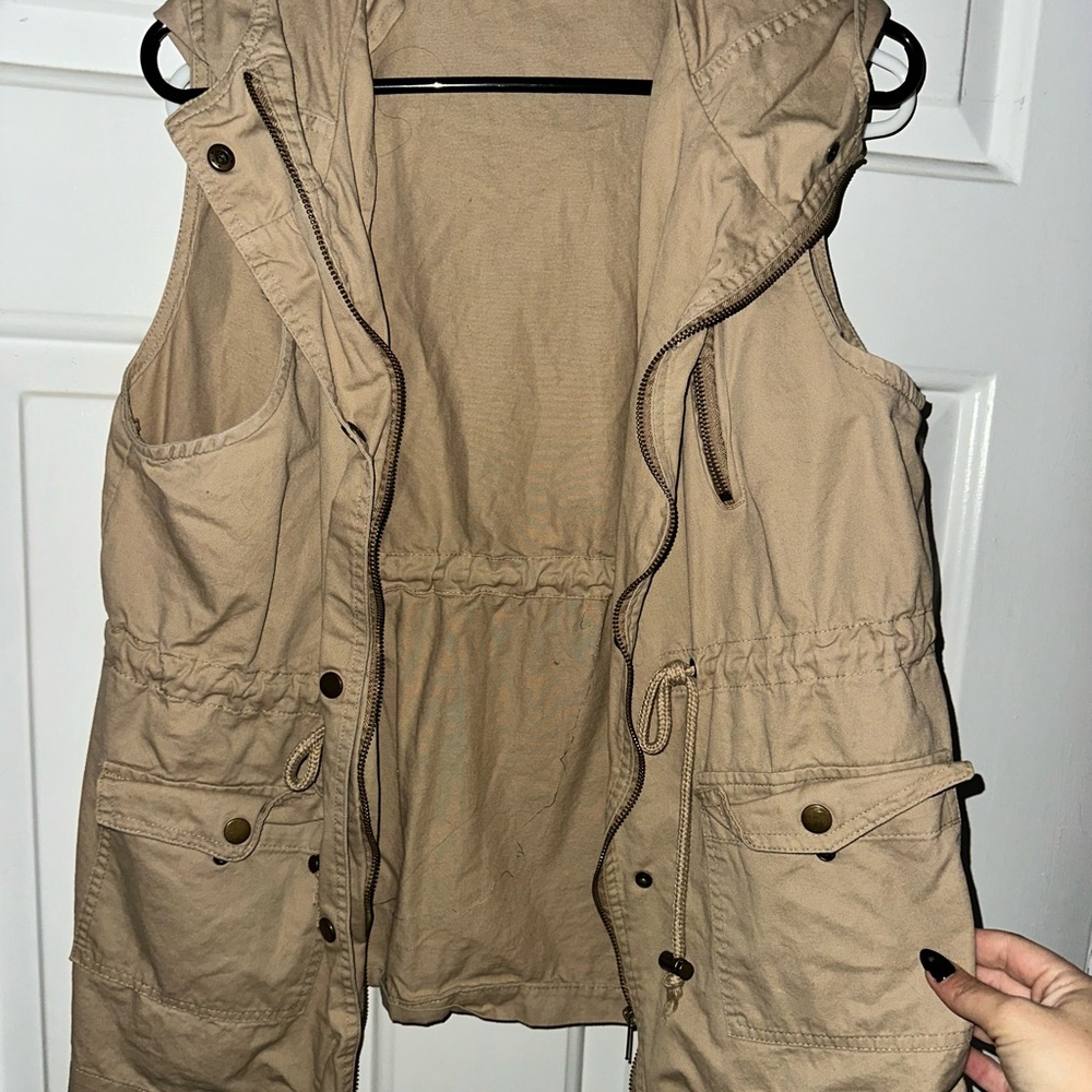 Women’s tan cargo vest with hood. Adjustable waist straps.